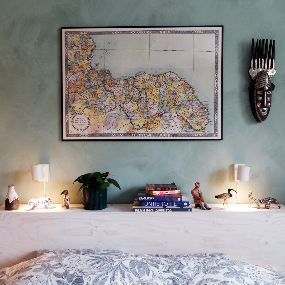 Full view of the framed Alkebu-Lan 1270 AH pre-colonial African continent map print hanging in the artist Nikolaj Jesper Cyon's bedroom, styled alongside his handmade ceramic art sculptures available in the shop and books featuring his cartographic work.