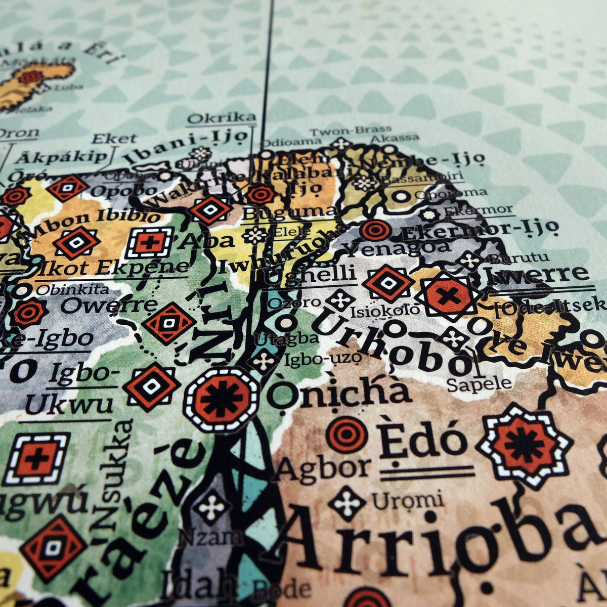 Detailed macro photograph of the Niger Delta and southeastern Nigeria on the Alkebu-Lan map print. Highlights the ancient Kingdom of Nri (spiritual heart of Igbo culture and origin of Things Fall Apart setting) and Ẹ̀dó [Benin City], famed for the Benin Bronzes. Features the Aro Confederacy (Omu Aro) trade realm, Warri [Iwerre], Itsekiri, and coastal Ijaw/Ijo kingdoms such as Ibani-Ijo (Bonny Kingdom, ruled by warrior Queen Kambasa) and Nembe-Ijo. Also depicts Urhobo, Mbon Ibibio, Efik, and the palm oil and