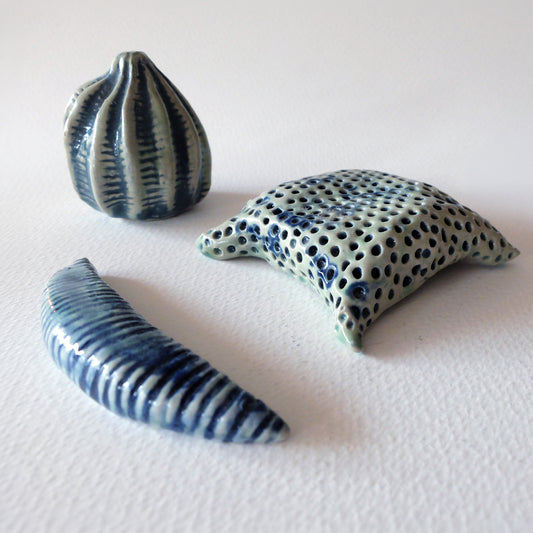 A set of three handcrafted ceramic micro-organism sculptures inspired by diatoms and pollen grains in blue and light green glazes, sculpted by Nikolaj Jesper Cyon.