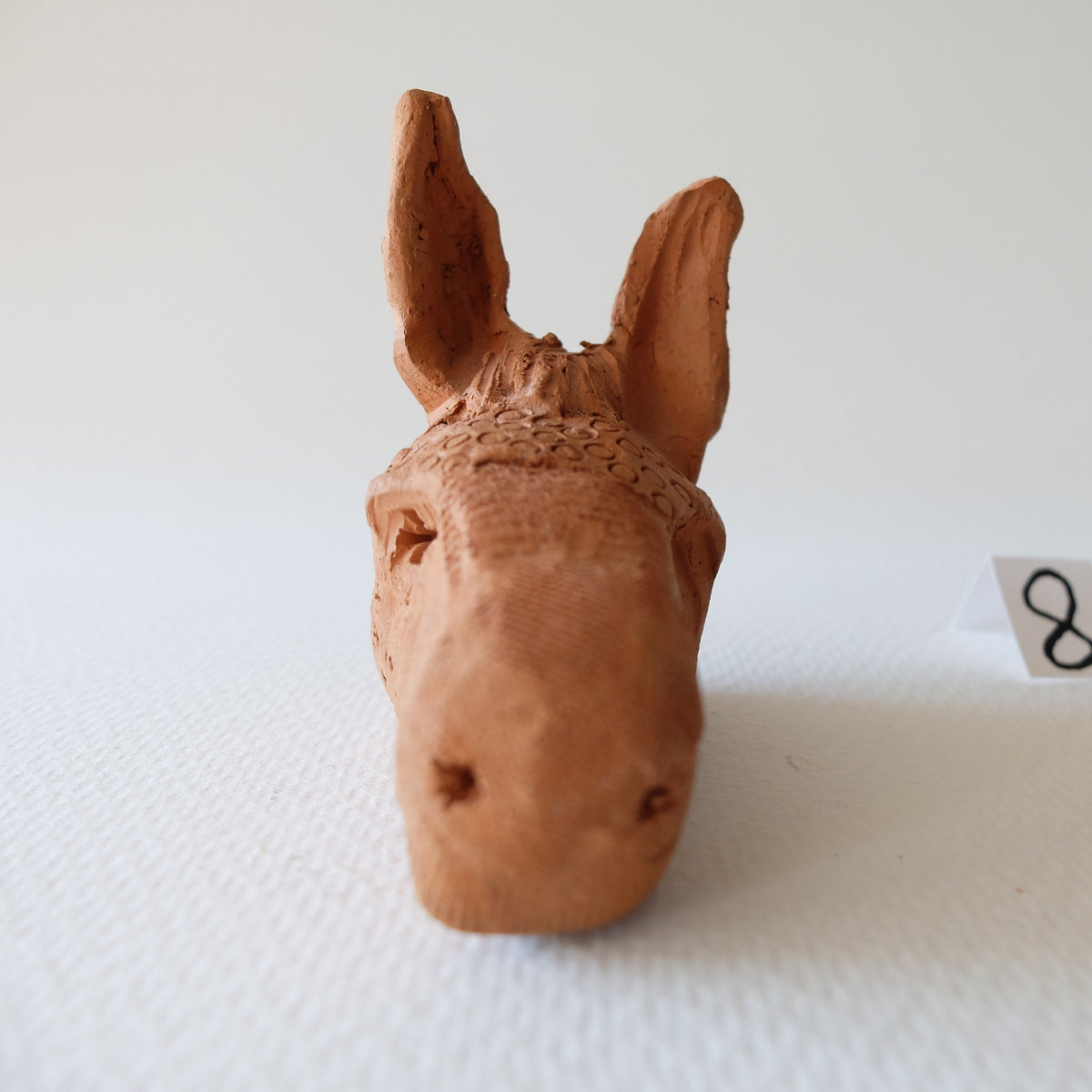 Handcrafted terracotta donkey head sculpture "The Babylonian Donkey (#8)" by Nikolaj Jesper Cyon. Front view showing its elongated muzzle and symmetrical ears.