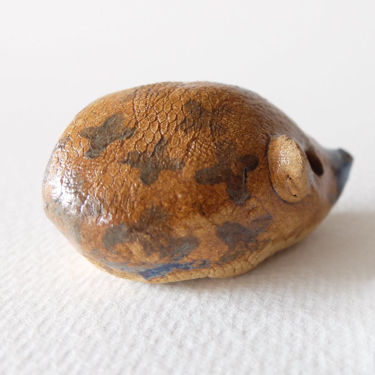 Handcrafted ceramic hedgehog figurine "The Chestnut Hedgehog (#5)" in stoneware by Nikolaj Jesper Cyon. Full side view showing blue-speckled details on the back.