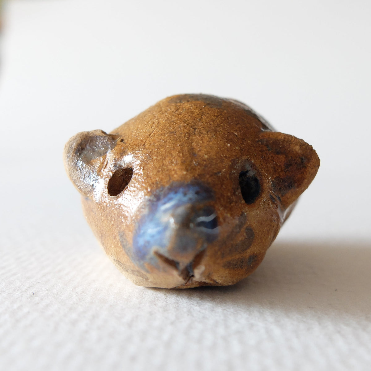 Handcrafted ceramic hedgehog figurine "The Chestnut Hedgehog (#5)" in stoneware by Nikolaj Jesper Cyon. Front close-up view highlighting the rounded ears, snout, and dark blue facial accents.