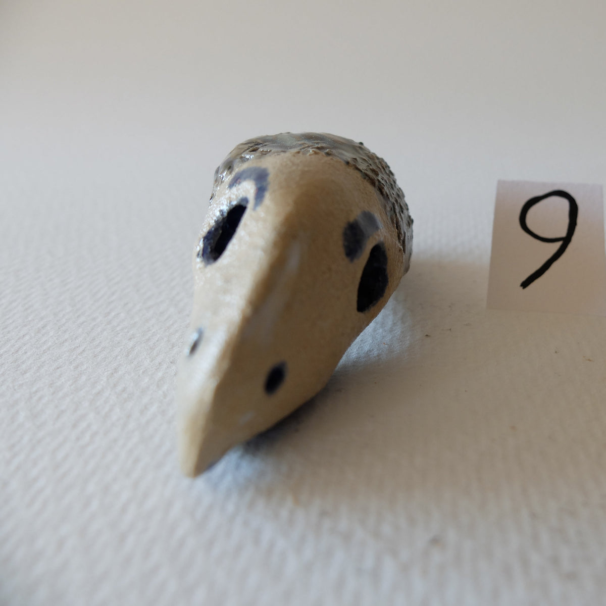 Handcrafted ceramic chimeric figurine "The Hedgehog Bird (#9)" in stoneware by Nikolaj Jesper Cyon. Front close-up view showing the face with distinct eye sockets and pointed beak.