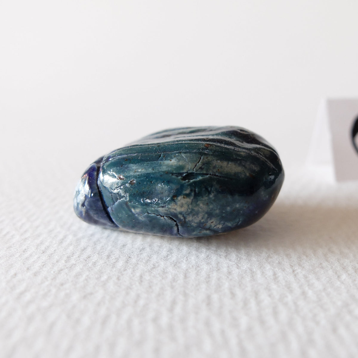 Handcrafted ceramic beetle figurine "The Jade Scarab (#6)" in stoneware by Nikolaj Jesper Cyon. Side profile view showing its low-profile sculpted shape and vibrant jade green glaze tones.