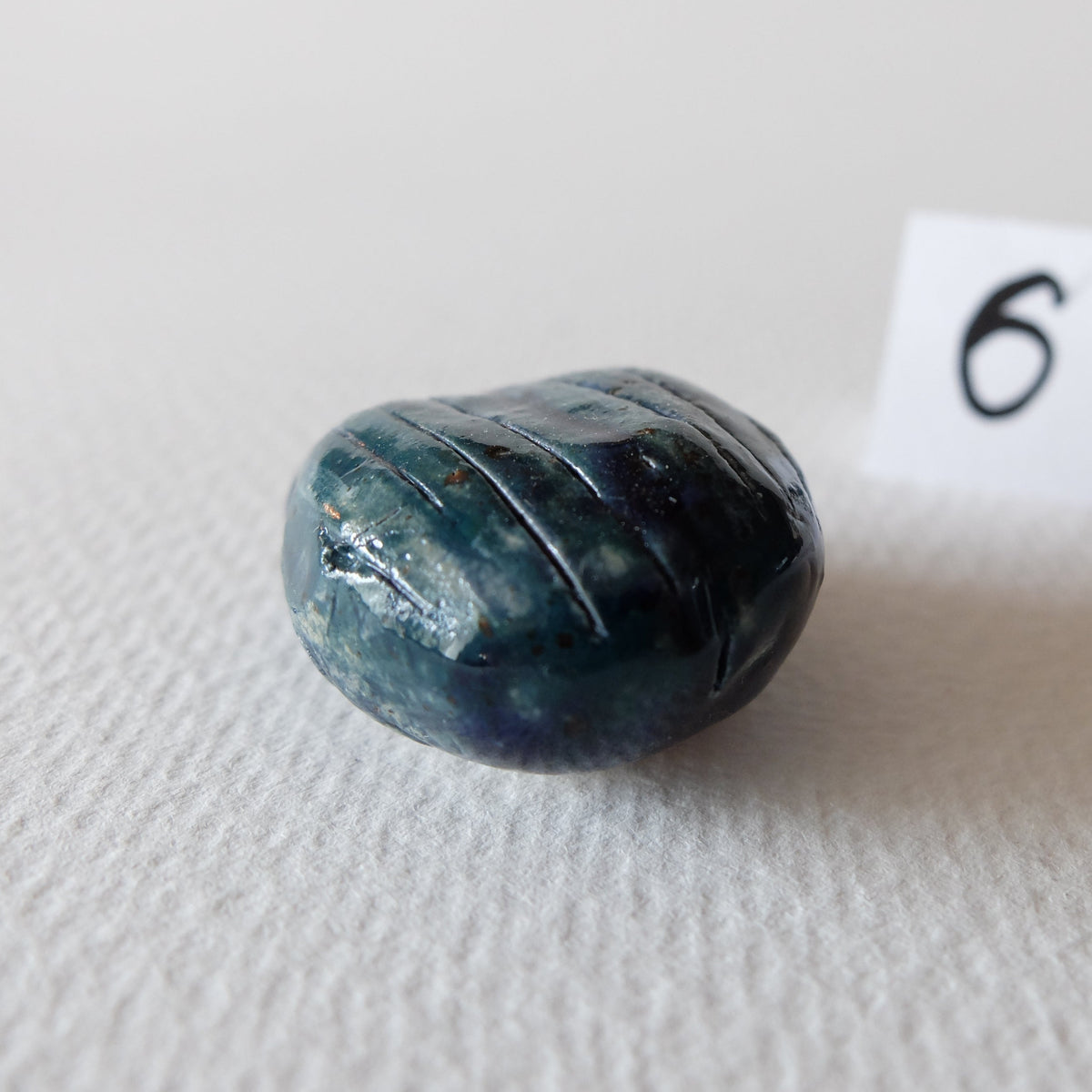 Handcrafted ceramic beetle figurine "The Jade Scarab (#6)" in stoneware by Nikolaj Jesper Cyon. Rear perspective view showing the carved lines and glossy jade-blue finish.