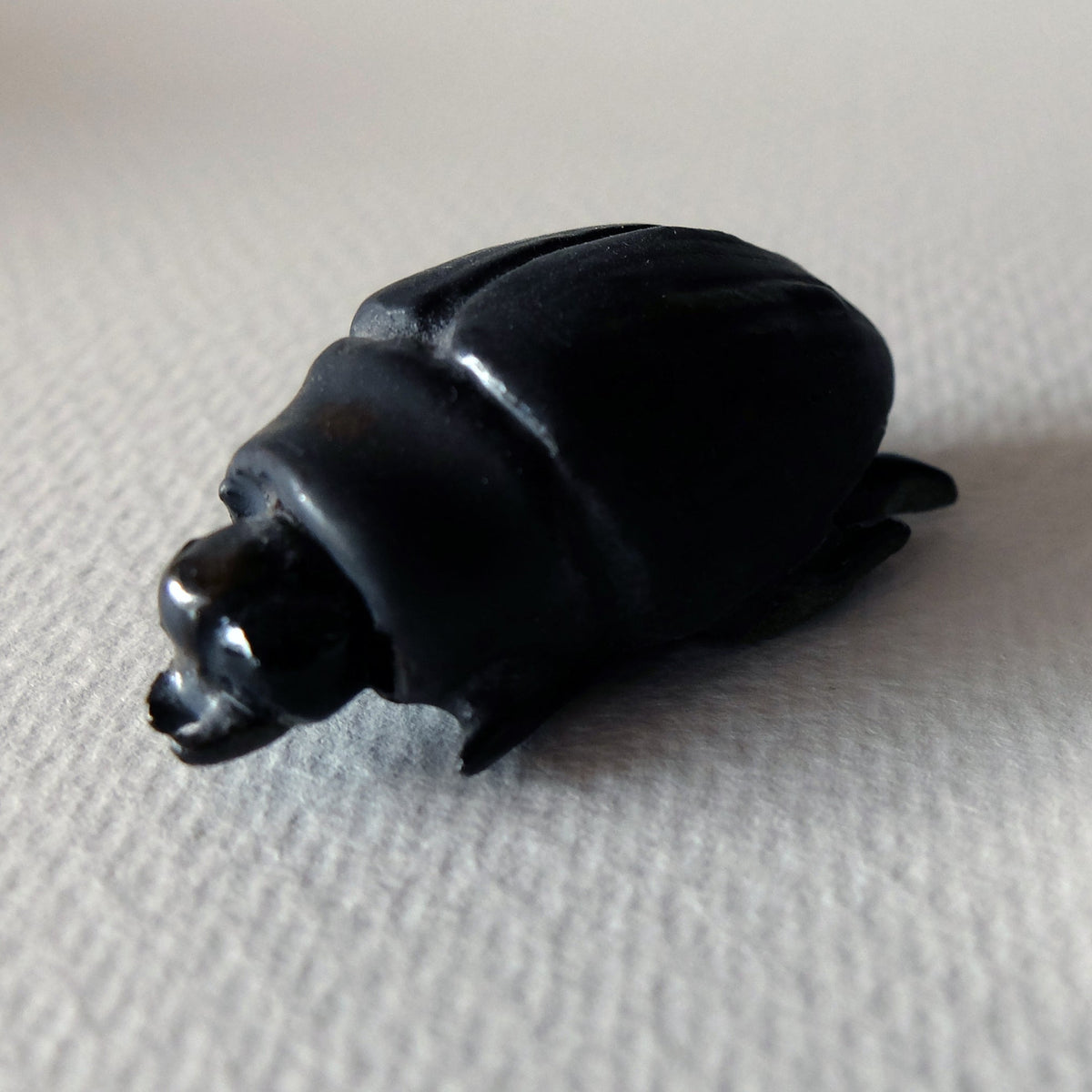 Handcrafted ceramic beetle figurine "The Obsidian Beetle (#2)" in stoneware by Nikolaj Jesper Cyon. Finished with a satin black glaze over a smooth, rounded carapace and sculpted anatomical insect details.