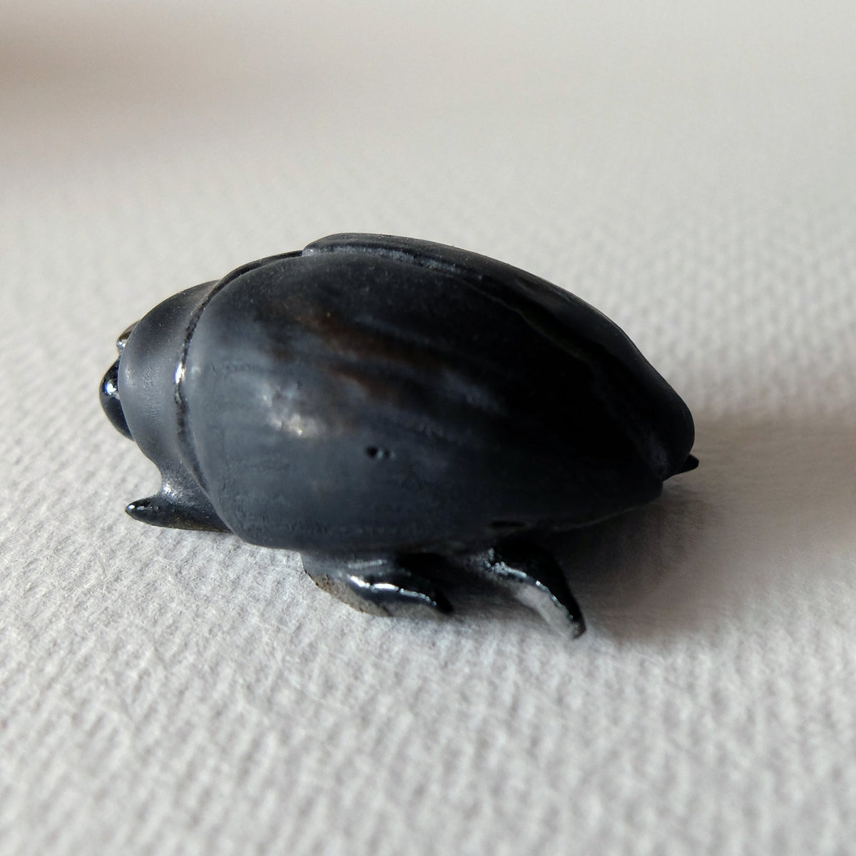 Handcrafted ceramic beetle figurine "The Midnight Beetle (#2)" in stoneware by Nikolaj Jesper Cyon. Side and rear profile view showing the dark, satin glaze.