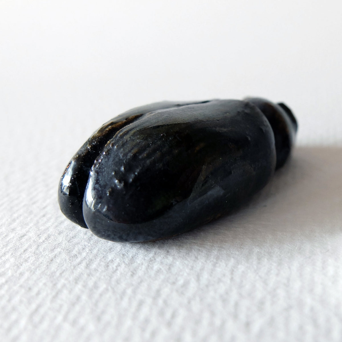 Handcrafted ceramic beetle figurine "The Obsidian Beetle (#4)" in stoneware by Nikolaj Jesper Cyon. Rear view highlighting the smooth, rounded obsidian-colored back.