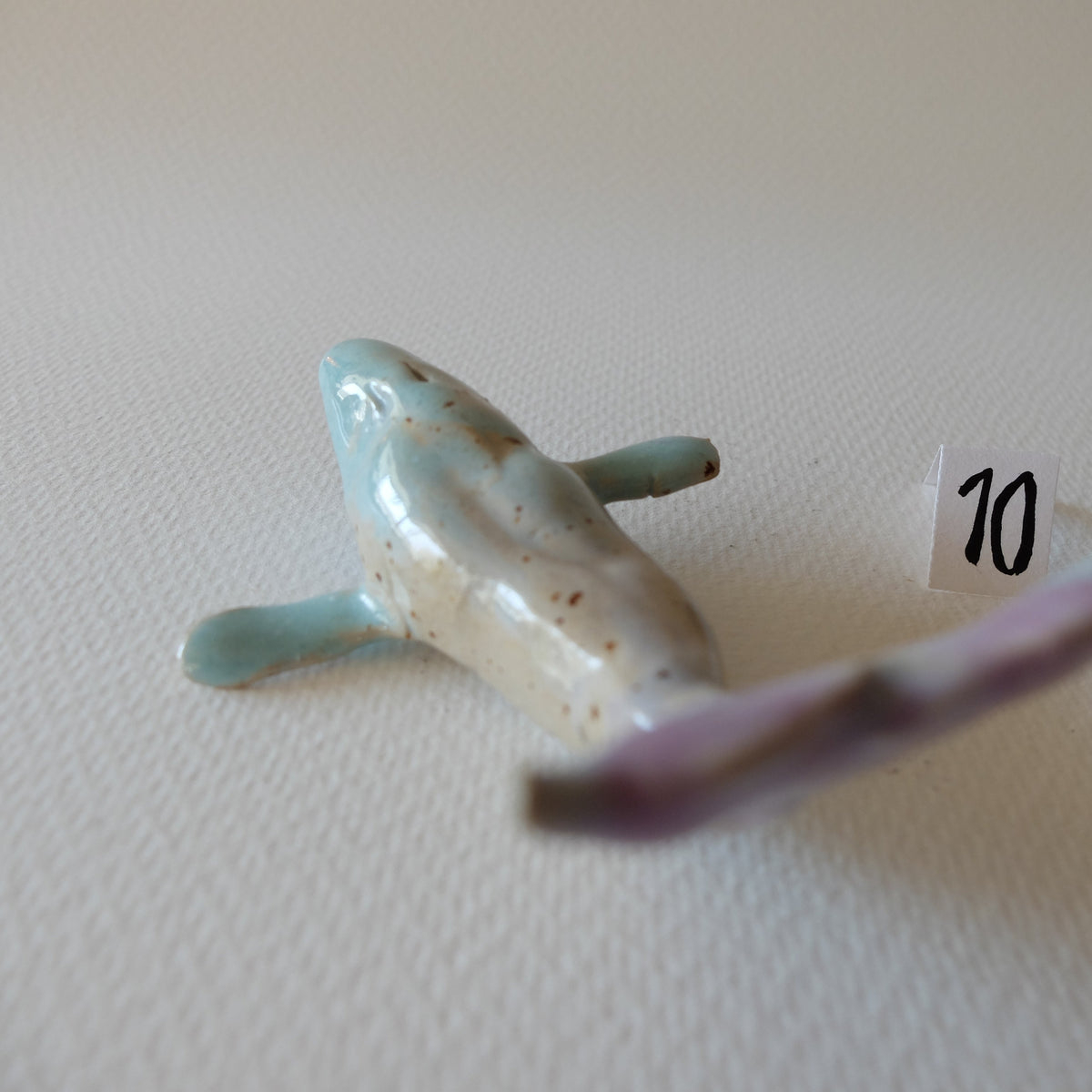Handcrafted ceramic whale figurine "The Pastel Whale (#10)" in stoneware by Nikolaj Jesper Cyon. Front view highlighting the sculpted fins, head, and turquoise glaze.