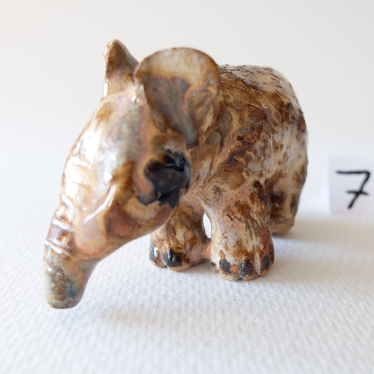 Handcrafted ceramic tapir figurine "The Spotted Tapir (#7)" in stoneware by Nikolaj Jesper Cyon. Front perspective view highlighting its distinct trunk-like snout and mottled brown glaze.